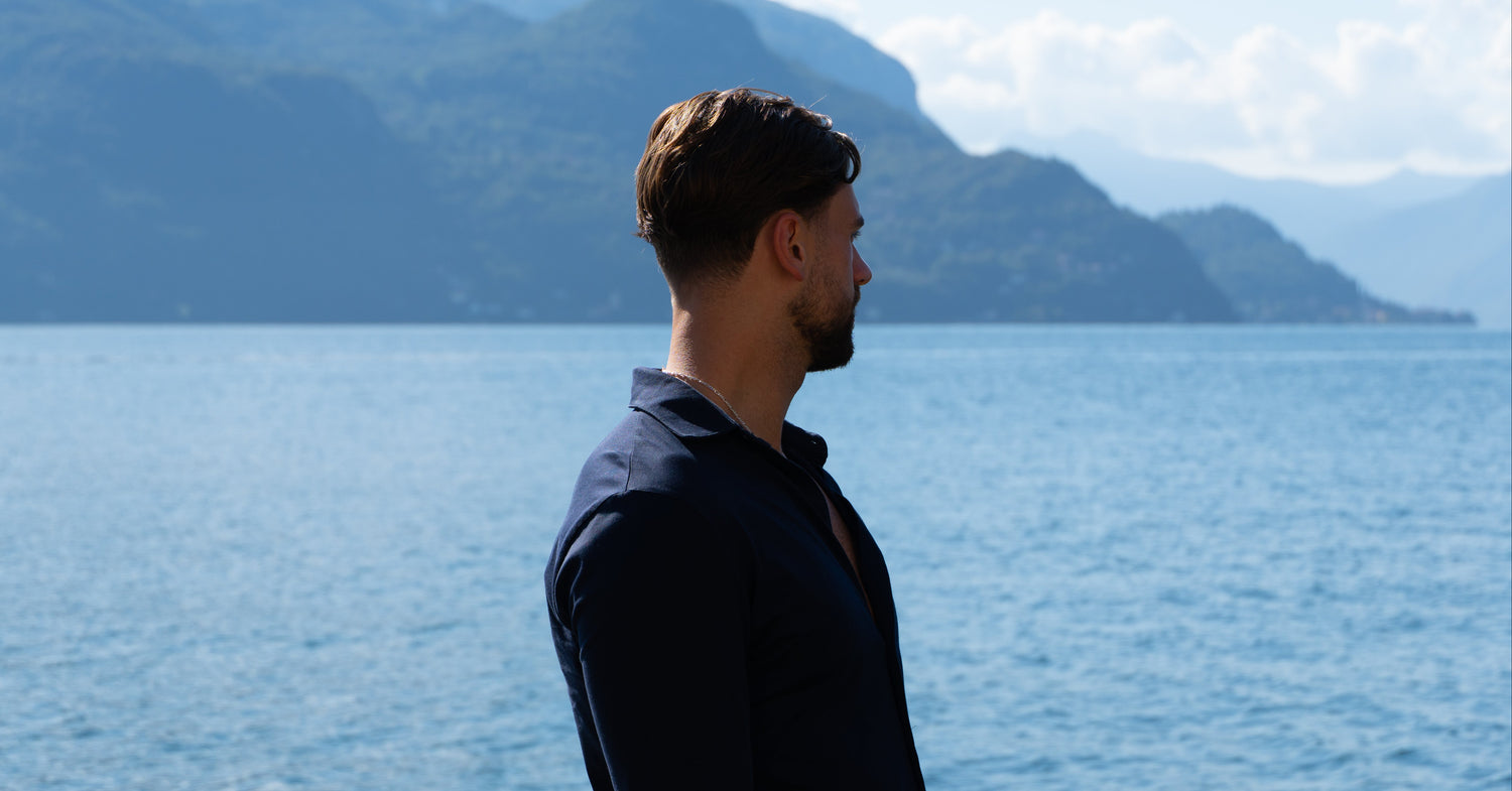 Man standing by a lake with mountains in the background